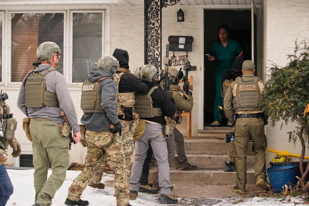 Teyana Gibson Brown, standing in her doorway, reacts after a federal immigration officer used a battering ram to break down her front door before arresting her husband, in Minneapolis, Jan. 11, 2026. (AP Photo/John Locher)